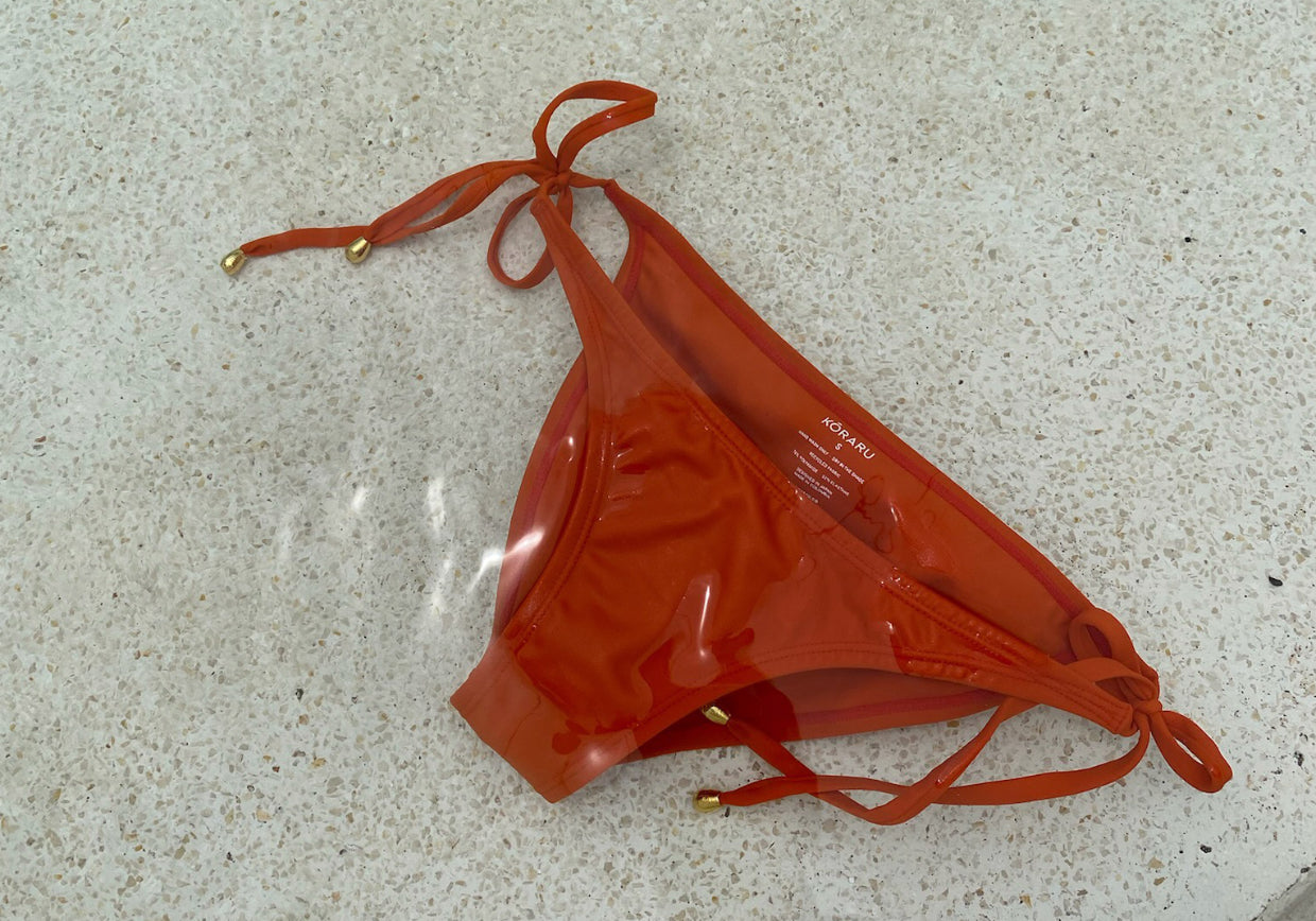 Koraru sustainable swimwear- orange side tie bikini bottoms in the pool