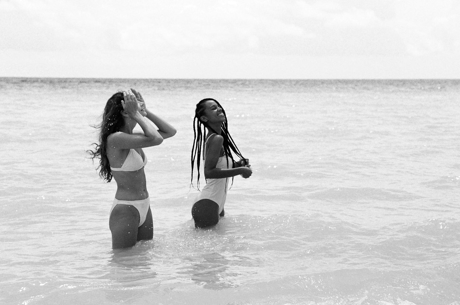 Models bathing in the water in Gili Meno wearing a pink one piece swimsuit and a pink classic bikini set by Koraru