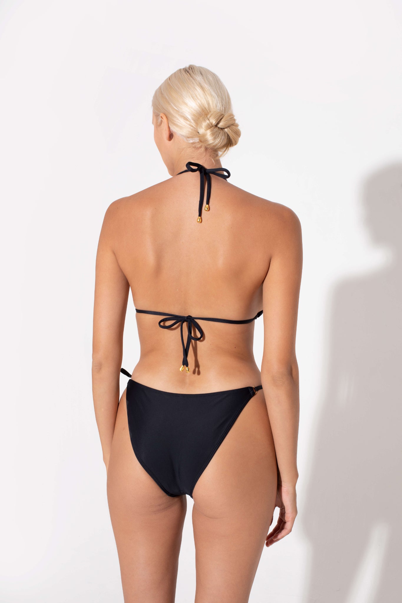 black bikini back side, gold accesories, classic and elegant design in black color and soft fabrics for swimwear